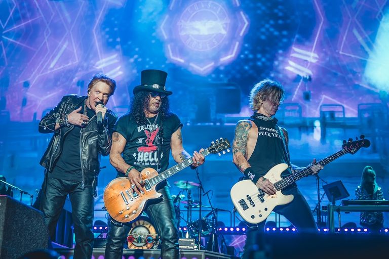Rock band Guns N' Roses performing live on stage with Axl Rose singing alongside Slash on guitar and Duff McKagan on bass.